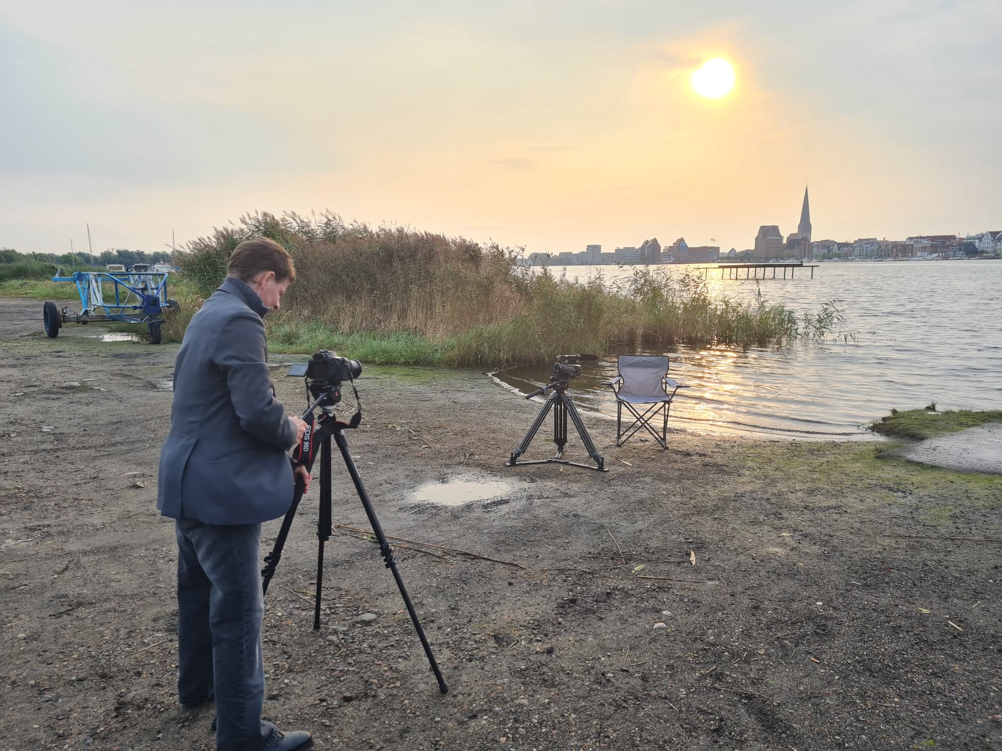 Drehvorbereitung am Wasser mit Kamera, Stativen und Blick auf eine Stadt